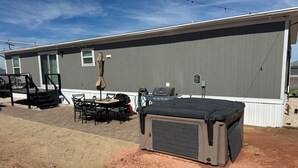 En bostadsbyggnad med en uteplats, utemöbler, en grill och ett överbyggt förråd.