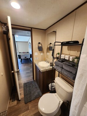 A compact bathroom with a toilet, sink, and a towel rack.