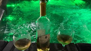A bottle of wine and two glasses on a tray in front of a green-lit bathtub. - A beautiful 2 bedroom apartment with sea views and hot tub .  (Pegeia)