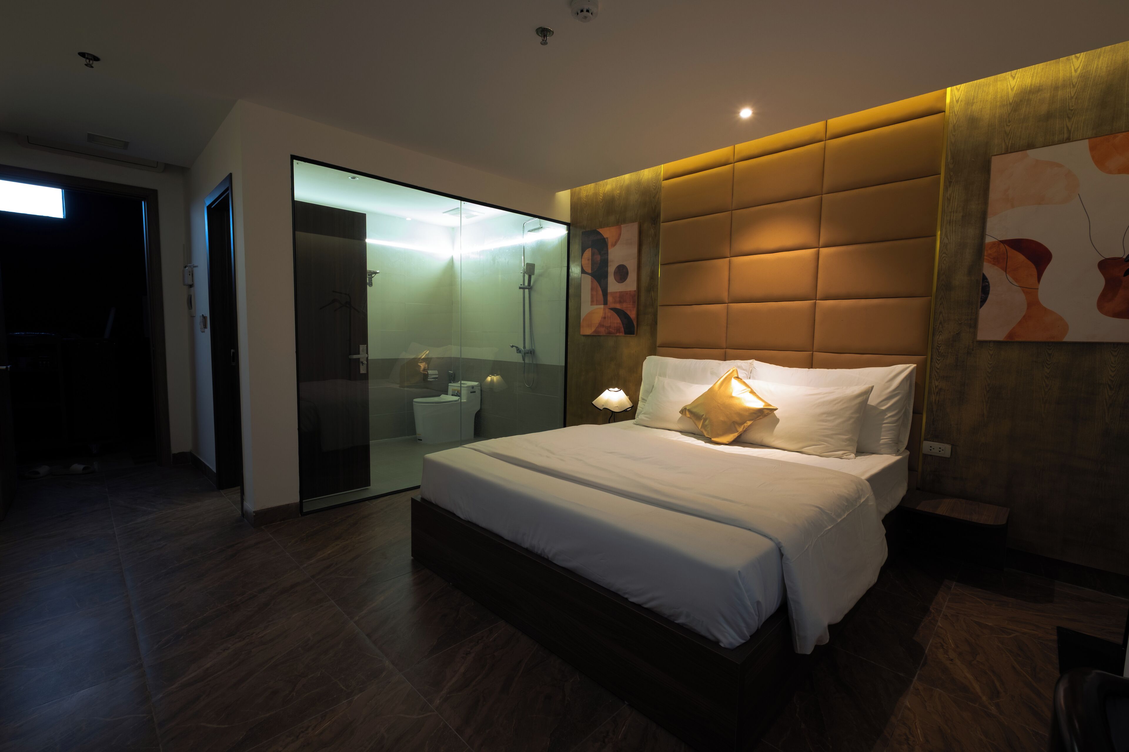 Une chambre moderne avec un grand lit, une douche en verre et une tête de lit en bois.