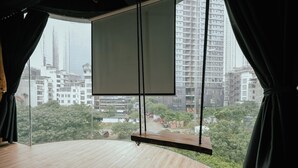 A room with a large window, a wooden floor, and a projector screen. - Love in the Atlantis Hotel (Hanoi)