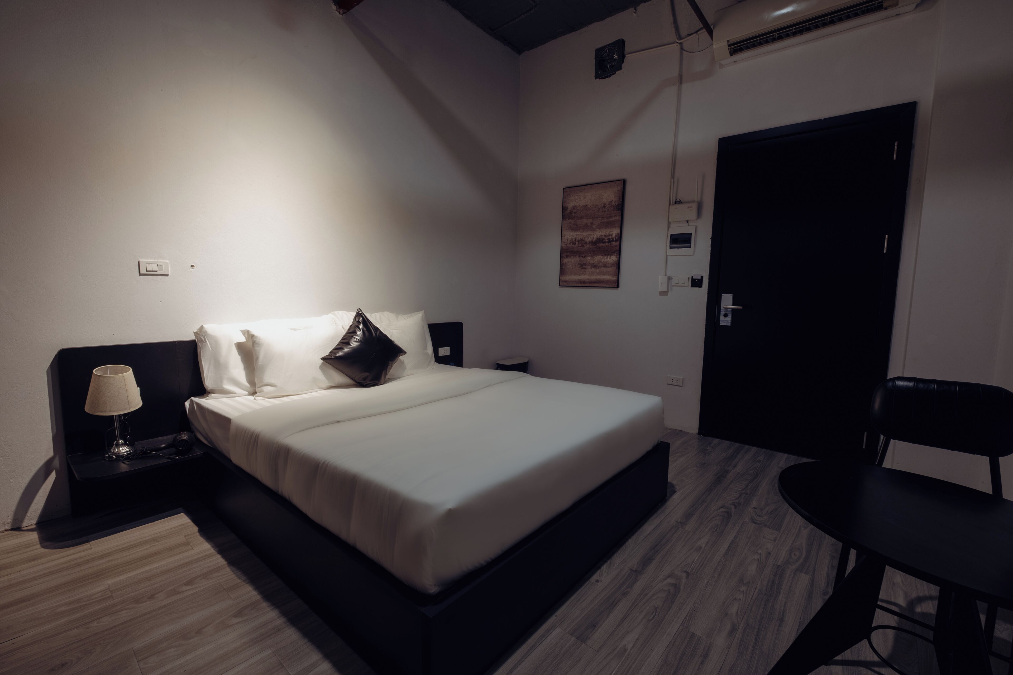 Une chambre à coucher avec un lit, des tables de chevet, une chaise et une porte.
