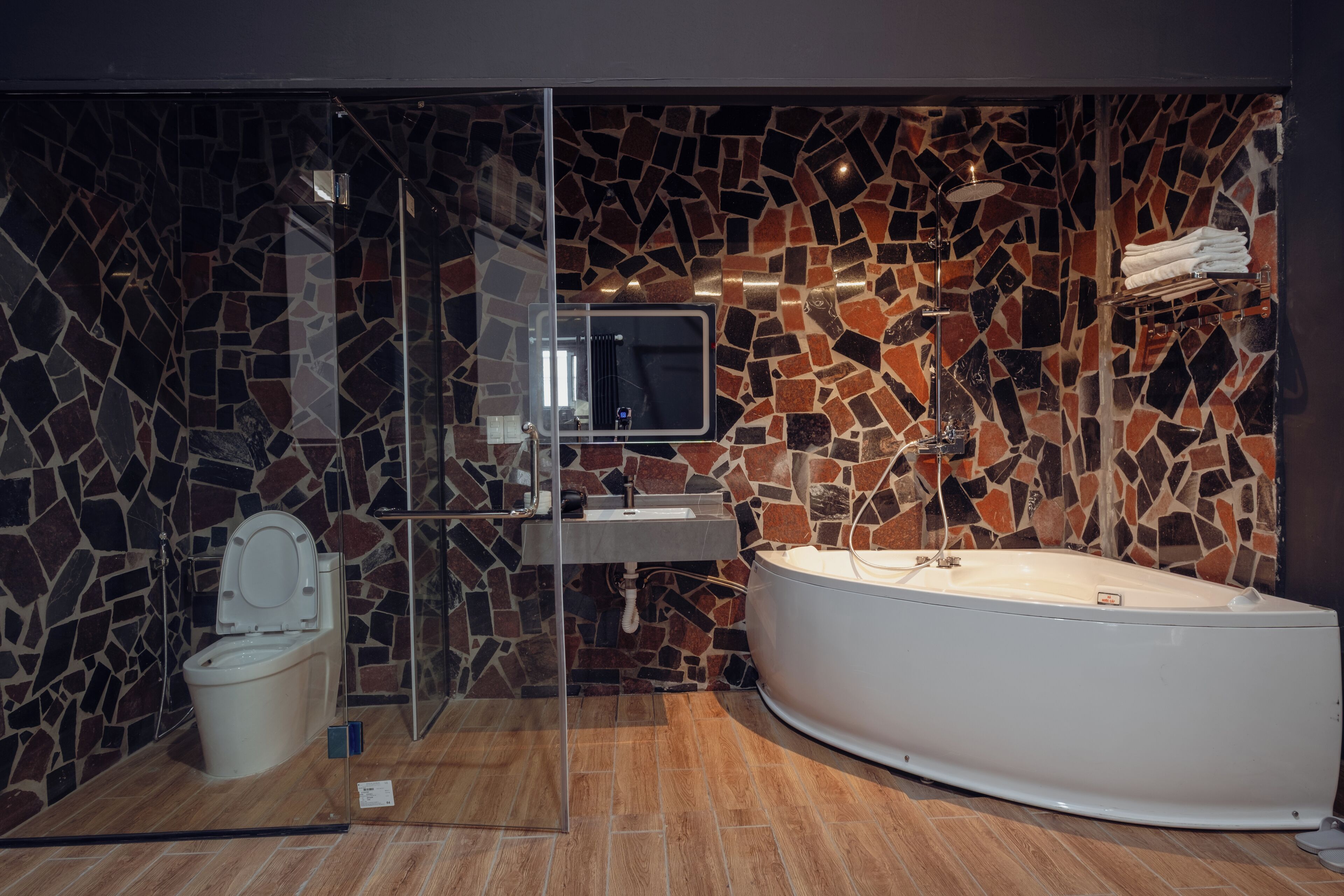 Une salle de bain moderne avec un mur en mosaïque, une douche à parois de verre, des toilettes, un lavabo et une baignoire sur pieds.
