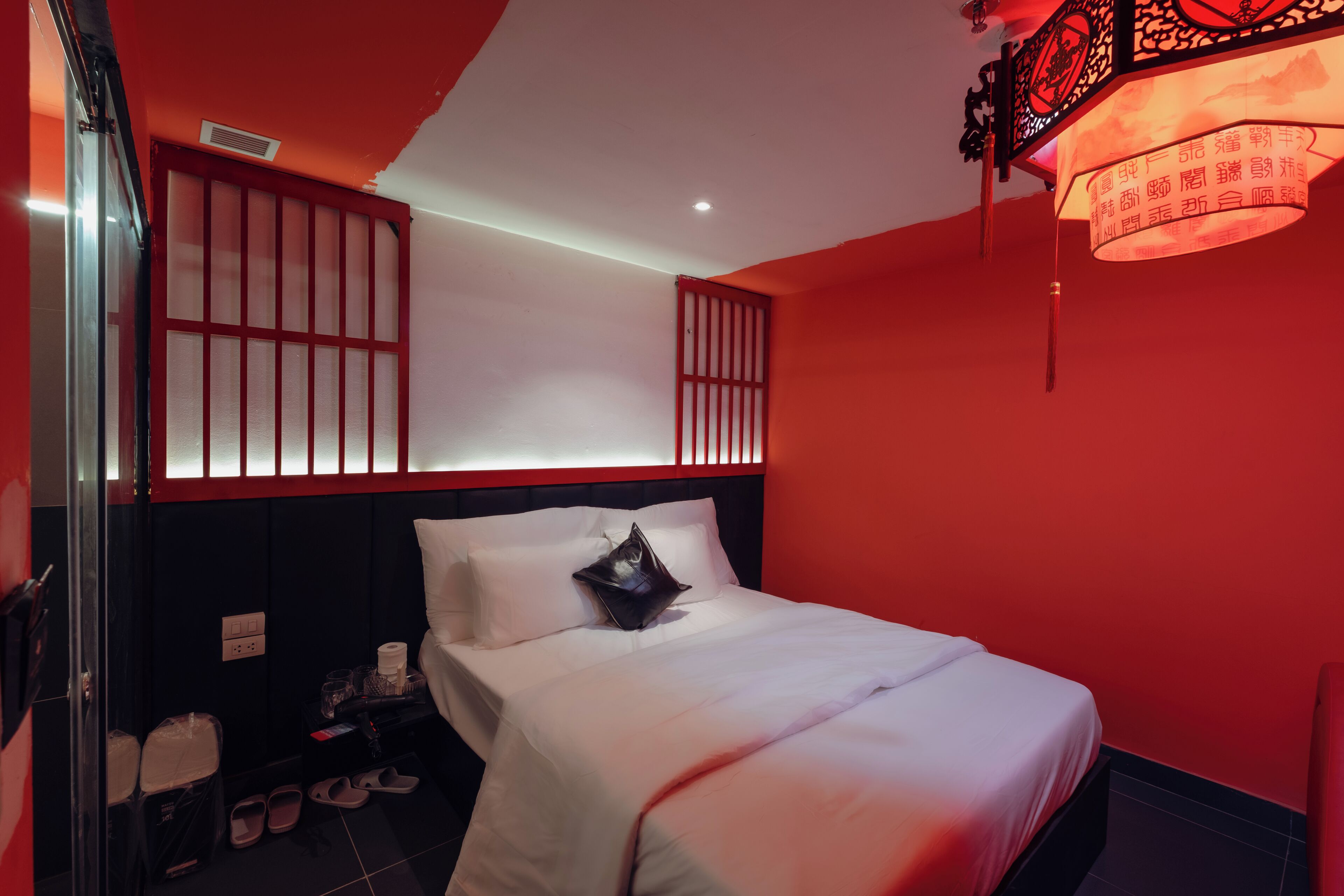 Ein Hotelzimmer mit einem Bett, einer roten Akzentwand, einem Fenster mit Blick und einer Deckenleuchte.