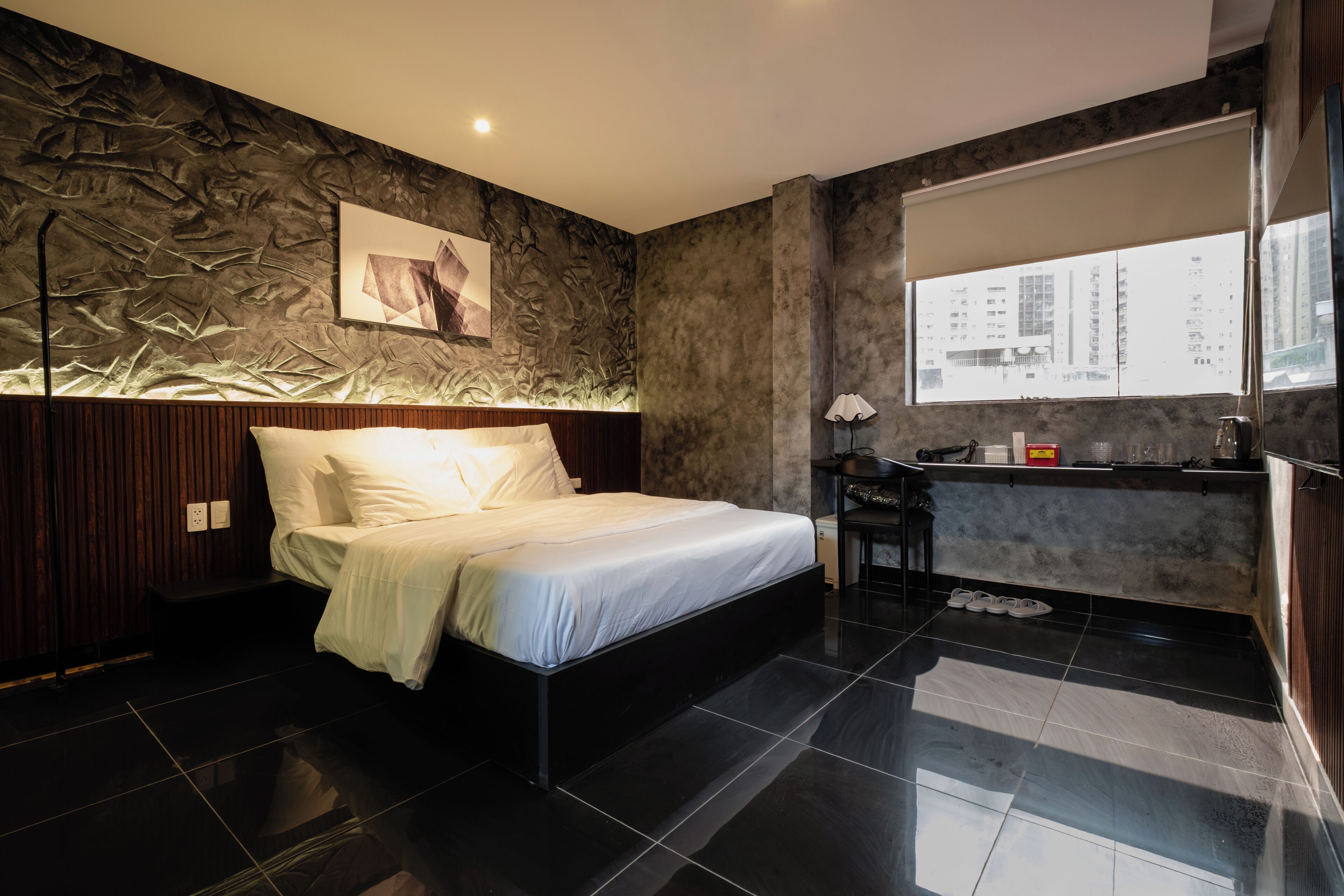 A modern bedroom with a bed, a desk, and a large window.