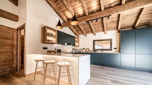Una cocina moderna con techo de madera, una isla central con taburetes y armarios azules.