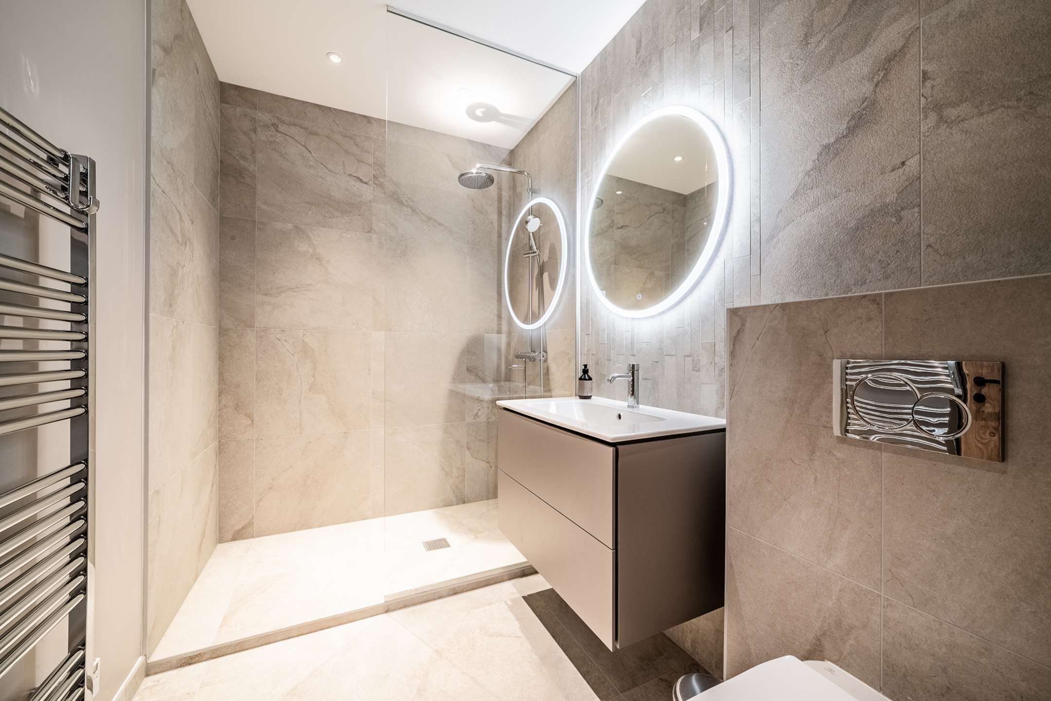 A modern bathroom with a walk-in shower, a vanity with a mirror, and a towel rack.
