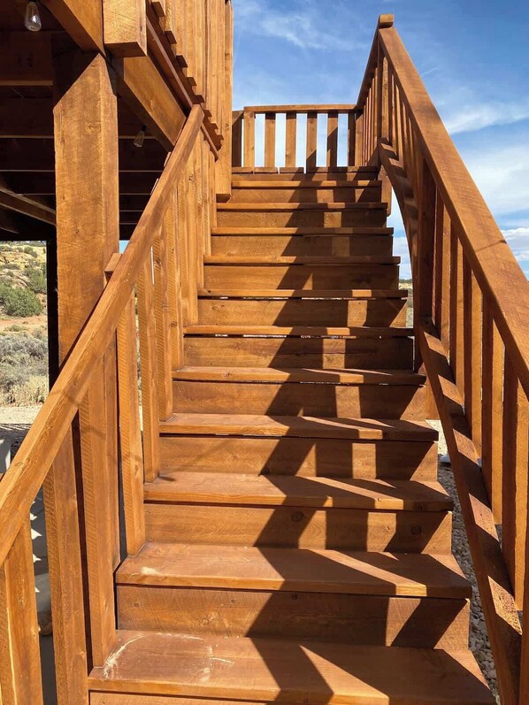 A wooden staircase with a railing, leading to an outdoor area.