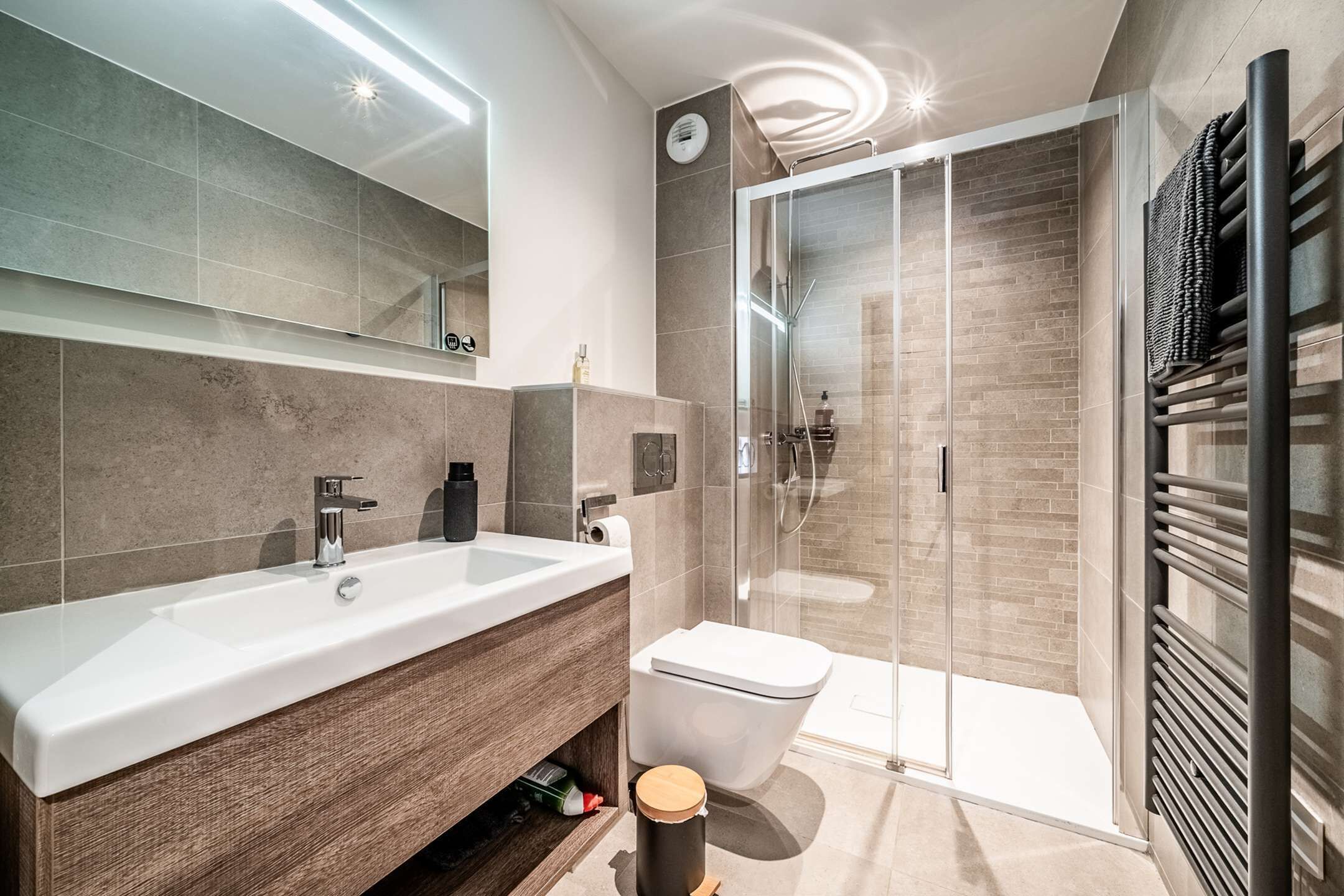 Een moderne badkamer met een groot wastafel, spiegel en een douchecabine van glas.