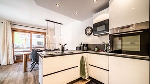 A modern kitchen with white cabinets, a built-in oven, and a clock on the wall.