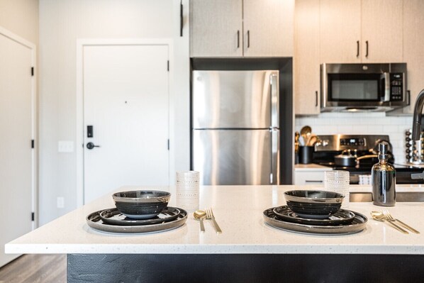 Una cocina moderna con electrodomésticos de acero inoxidable, una puerta blanca y un diseño limpio y minimalista.