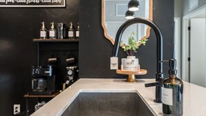 A modern kitchen with a large sink, a coffee machine, and a shelf with bottles. - Greenbelt Balcony 2BR | Hot Tub, Steps to Downtown (Boise)