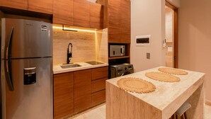 Una cocina moderna con armarios de madera, electrodomésticos de acero inoxidable, un microondas integrado y encimera de mármol.