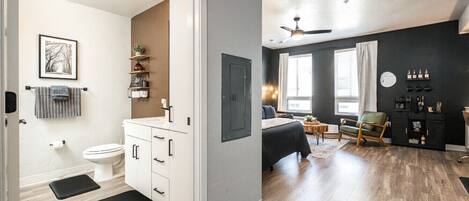 A modern apartment with a bathroom, kitchenette, and living area.