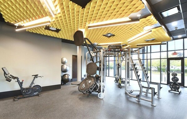 Un gimnasio con equipo de ejercicio, una bicicleta estática y un techo con diseño de panal.