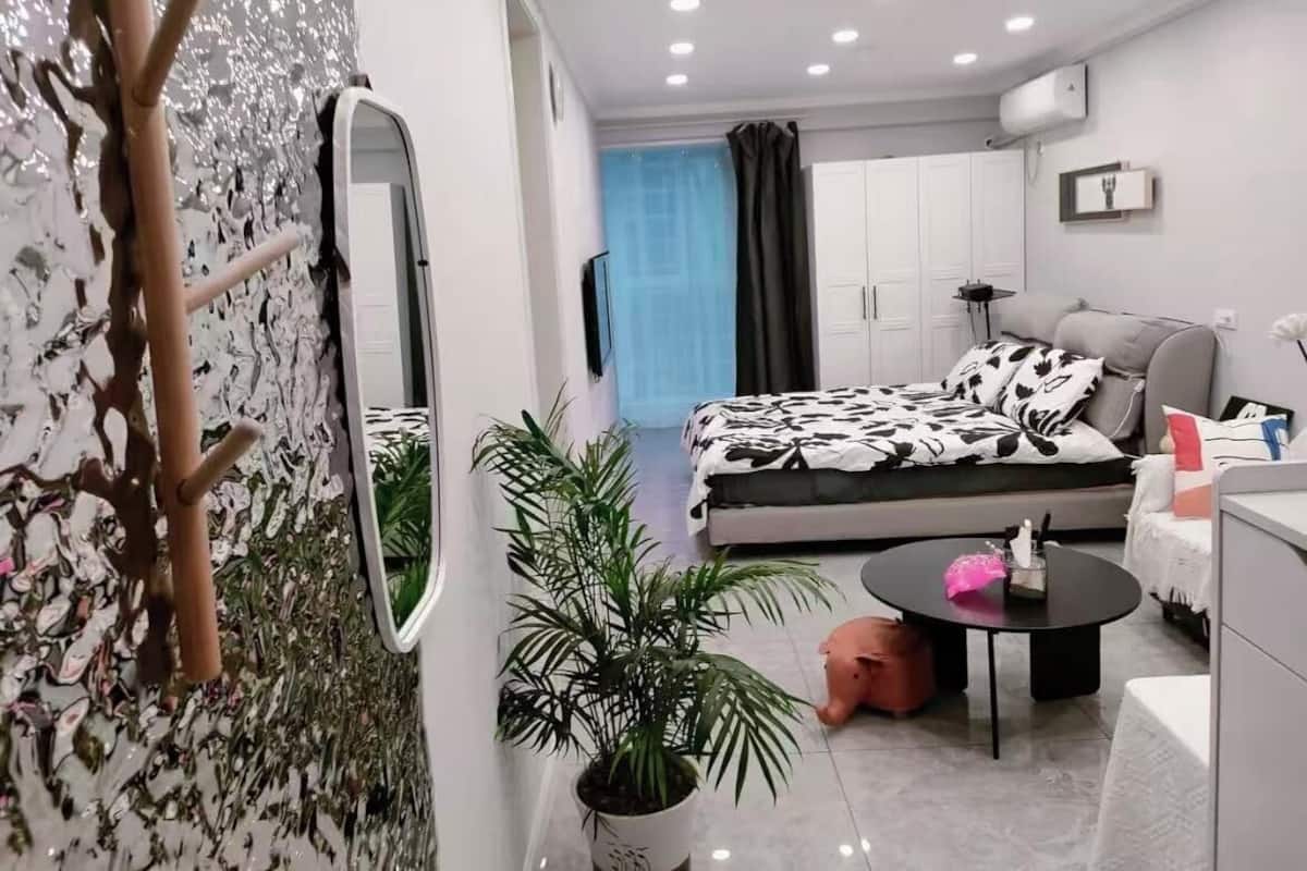 A modern bedroom with a bed, bedside table, and a potted plant.