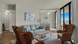 Un salon comprenant un canapé, deux fauteuils, une table basse et un tableau accroché au mur.
