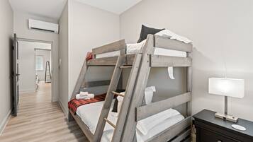 A bunk bed with a ladder, a bedside table with a lamp, and a door leading to a bathroom.