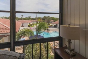 A room with a view of a swimming pool and neighboring houses. - Modern 2BR | Pool View | Steps to Crescent Beach (Sarasota)