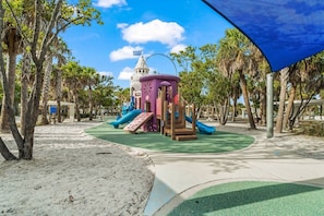 A playground with a castle-like structure, slides, and a sandy area. - Modern 2BR | Pool View | Steps to Crescent Beach (Sarasota)