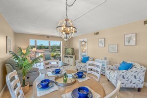 A dining area with a round table, chairs, and blue bowls. There is a chandelier above the table. - Modern 2BR | Pool View | Steps to Crescent Beach (Sarasota)