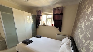 A bedroom with a bed, a wardrobe, a radiator, and a window with curtains. - Homely flat in Surrey, Sleeps 3, family friendly (Walton-on-Thames)