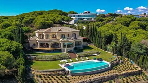 A large house with a swimming pool, surrounded by lush greenery and a well-maintained garden. - 8 bedroom luxury villa + sea, golf course and mountain views (Sotogrande)