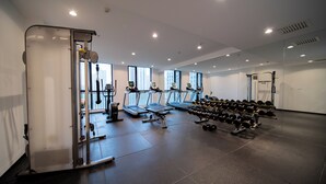 A gym with treadmills, a weight bench, and dumbbells. - xihe Langyue Hotel  (Beijing)