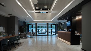 A modern hotel lobby with a reception desk, seating area, and large windows offering a view of the outdoors. - xihe Langyue Hotel  (Beijing)