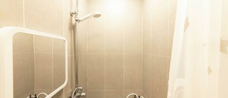 A small bathroom with a shower, a mirror, and two shelves with bottles.
