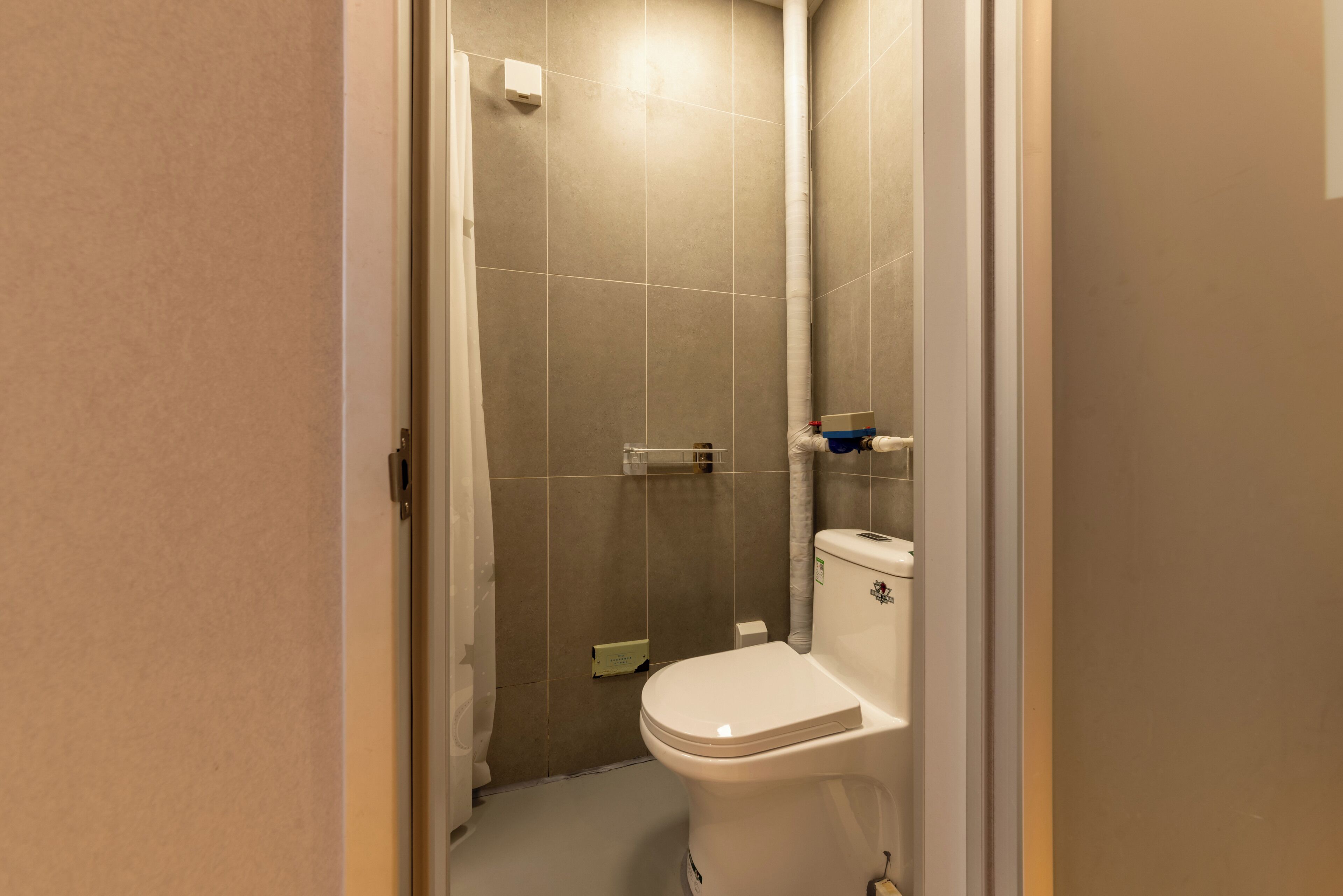 A bathroom with a toilet, a shower, and a towel rack.