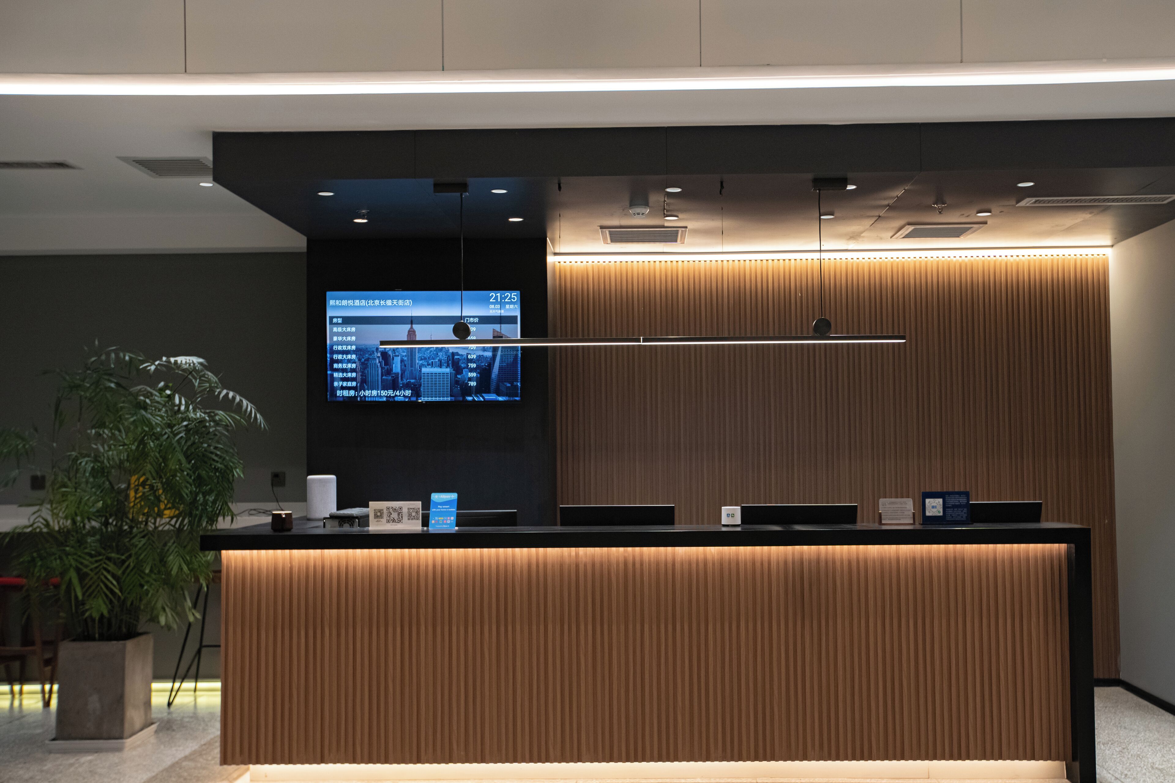 A modern reception desk with a digital screen displaying the time and cityscape.