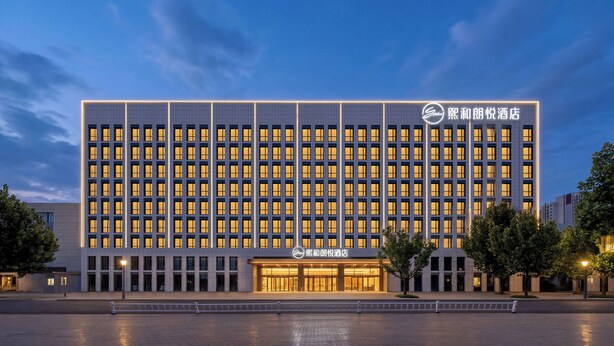 A modern hotel building with a grid of windows, a prominent entrance, and a clear sky. - xihe Langyue Hotel  (Beijing)