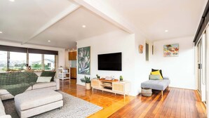 A modern living room with a sofa, ottoman, and a TV on a stand.
