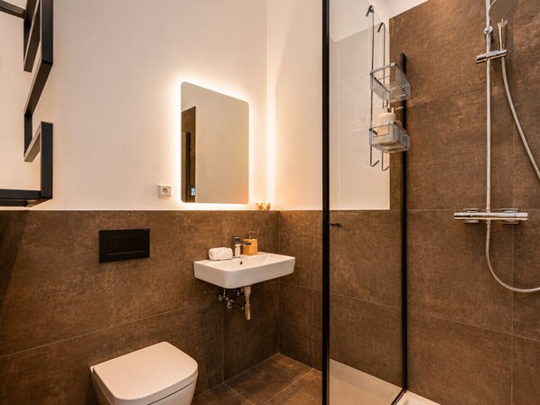 Une salle de bain moderne avec un lavabo blanc, des toilettes et un espace douche.