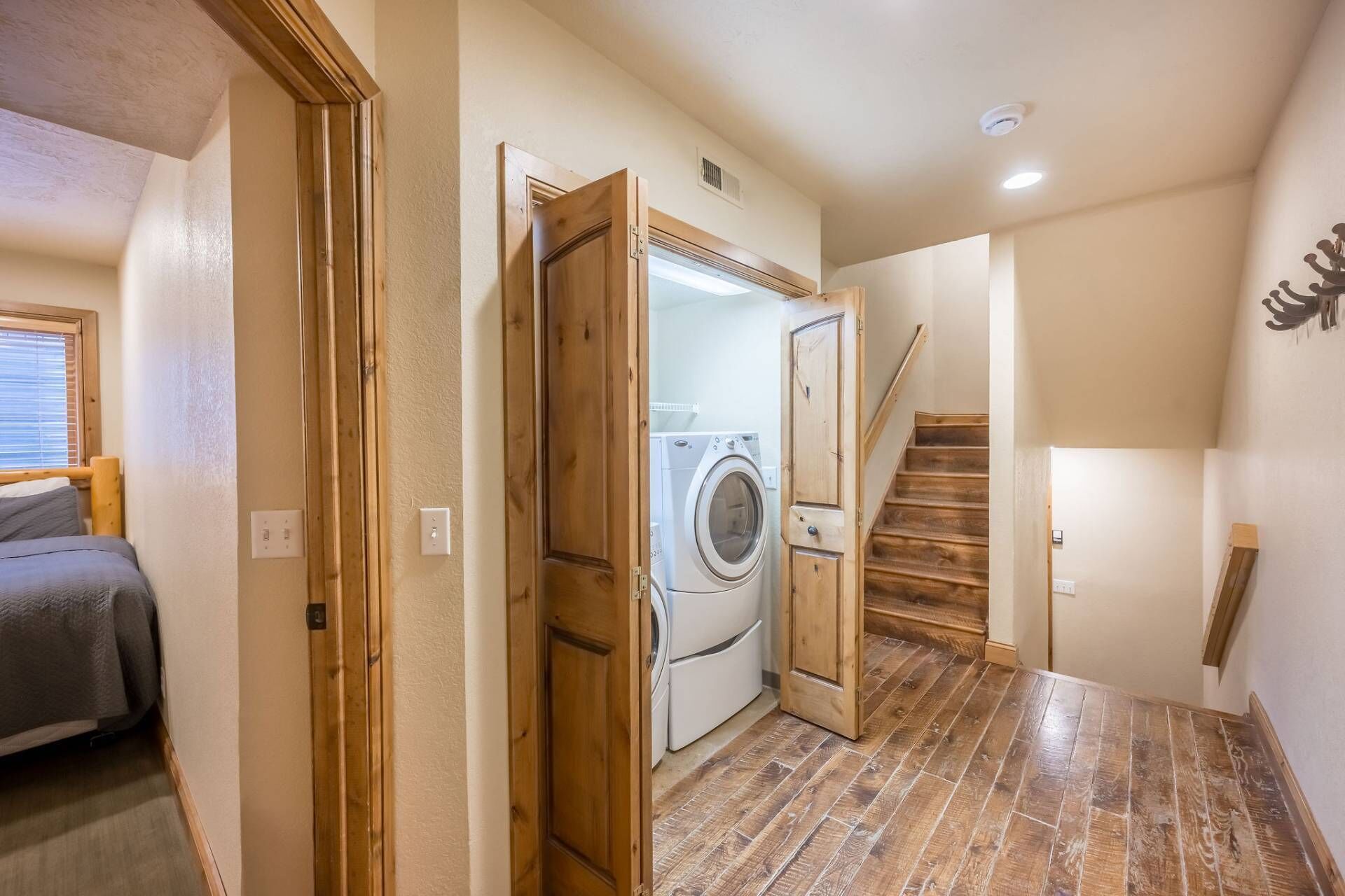 Une buanderie équipée d’un lave-linge et d’un sèche-linge, avec un plancher en bois et un escalier menant à un autre niveau.
