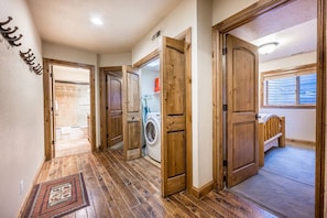 A hallway with wooden doors leading to various rooms, including a laundry area with a washing machine.