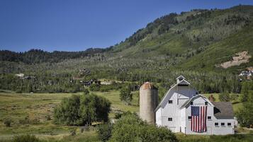 A white barn with an American flag, a silo, and a mountain backdrop.