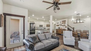 A spacious living room with a leather sofa, a coffee table, and a dining area with chairs and a table. - Aspen Crest Condo, 4BR, Deer Valley, hot tub (Kamas)