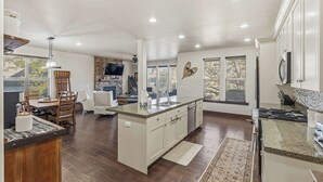 A spacious kitchen with a central island, wooden flooring, and a large window providing natural light. - Aspen Crest Condo, 4BR, Deer Valley, hot tub (Kamas)