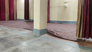 A room with a tiled floor, red curtains, and a stage area.