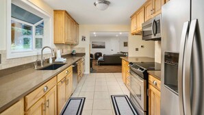 Una cocina moderna con armarios de madera, electrodomésticos de acero inoxidable y un amplio ventanal.
