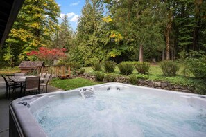 A hot tub on a patio with a stone wall and a wooden deck. - Alpine Getaway w/ Hot Tub, Firepit & Stunning Views, Pet Friendly, Near Mt. Hood Slopes (Welches)