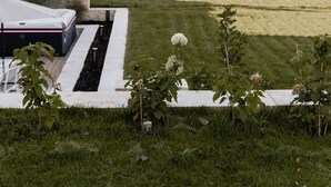 A well-maintained lawn with a white structure, possibly a shed, and a small garden area with plants. - Exclusive whirlpool apartment & mountain view (Steinhöring)