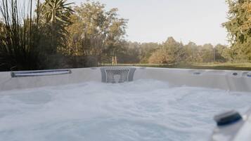 Een hottub omgeven door bomen en een hek.