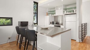 Una cocina moderna con una isla central, taburetes de bar, microondas y refrigerador.