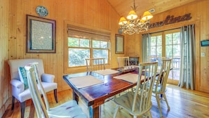 A wooden interior with a dining table, chairs, a chandelier, and large windows. - Scenic Mtn & Fairway Views: Cozy Cashiers Getaway (Cashiers)