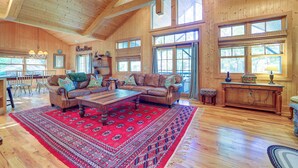 A spacious living room with a large wooden ceiling, a red patterned rug, leather sofas, and a wooden coffee table. - Scenic Mtn & Fairway Views: Cozy Cashiers Getaway (Cashiers)