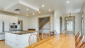 Una cocina amplia con armarios blancos, una mesa de comedor de madera y una escalera que sube a otro nivel.