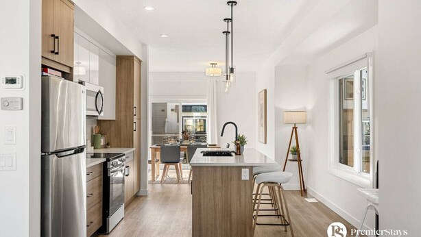 Une cuisine moderne dotée d’un réfrigérateur en acier inoxydable, de meubles en bois et d’un îlot central avec des tabourets de bar.